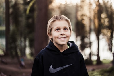 身穿黑色Nike套衫的男孩微笑的特写照片